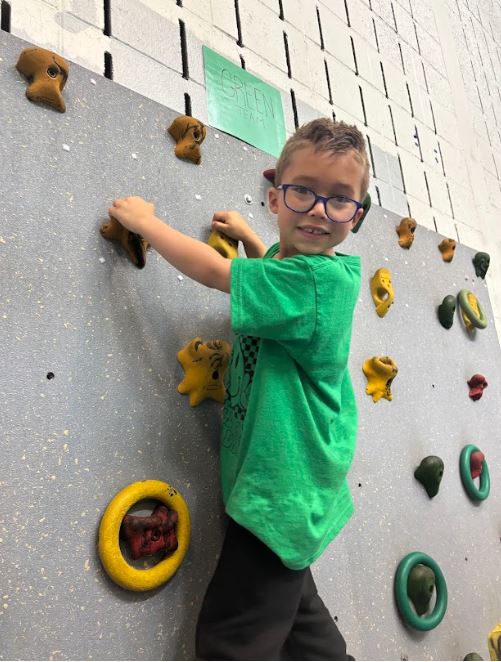 Student climbing a rock wall in the gymnasium